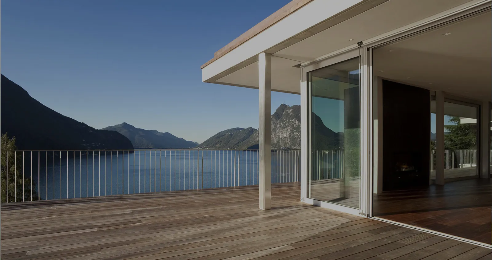 Villa équipée de fenêtres panoramiques coulissantes, terrasse bois avec balustrade blanche